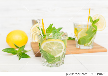 Mojito cocktail. Refreshing mojito cocktail with lime, lemon and mint in a tall glass with a stick Mojito cocktail. Refreshing mojito cocktail with lime, lemon and mint in a tall glass with a stick 95249023