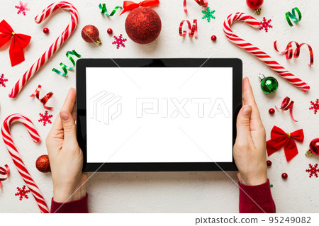 Christmas online shopping from home, female hands holding tablet pc with blank white display top view. woman hand holding tablet with blank screen, Christmas tree and gifts on background Christmas online shopping from home, female hands holding tablet pc with blank white display top view. woman hand holding tablet with blank screen, Christmas tree and gifts on background 95249082