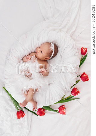 sweet newborn baby in dress with feathers 95249283