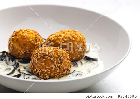 chickpeas balls with creamy black olives sauce 95249599