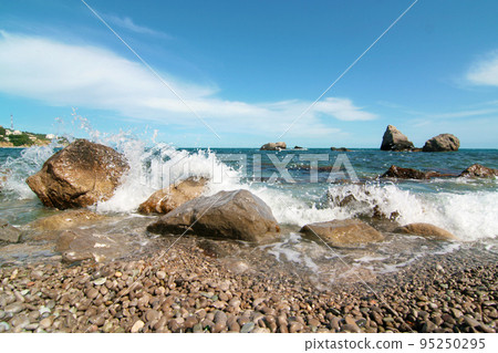 A rocky seashore with large stones in the water A rocky seashore with large stones in the water 95250295
