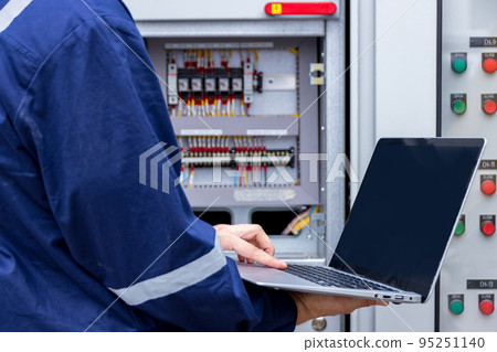 Electrical engineer  working with use laptop near Power Distribution Cabinet in the control room 95251140