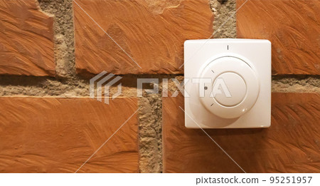Modern white room and floor heating controller on a brick wall, close-up. Adjustment of the comfortable temperature in the room. Copy space for text Modern white room and floor heating controller on a brick wall, close-up. Adjustment of the comfortable temperature in the room. Copy space for text 95251957