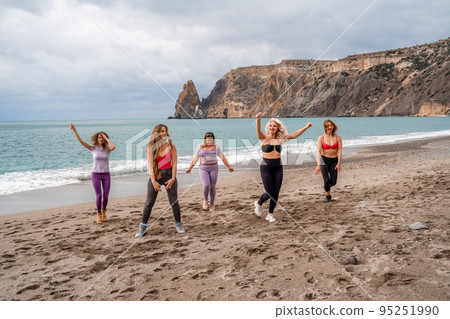 A group of five female friends are doing exercises on the beach. Beach holiday concept, healthy lifestyle 95251990