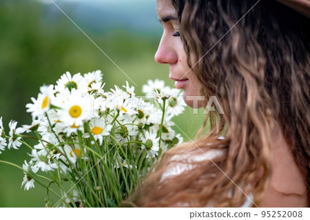A middle-aged woman holds a large bouquet of daisies in her hands. Wildflowers for congratulations 95252008