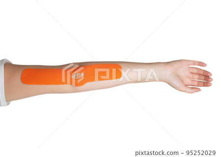 A woman's hand on which an orange kinesiological tape is glued to fix muscles and a joint. Alternative medicine, taping, isolate. Close-up 95252029