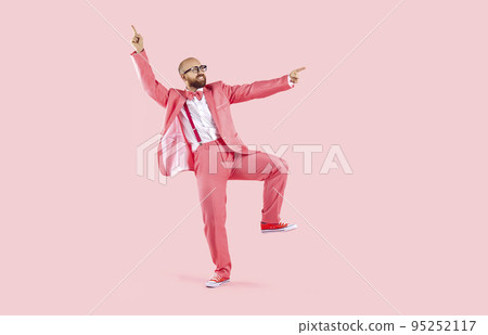 Funny dancer in pink suit, trainers and glasses dancing and having fun in studio 95252117