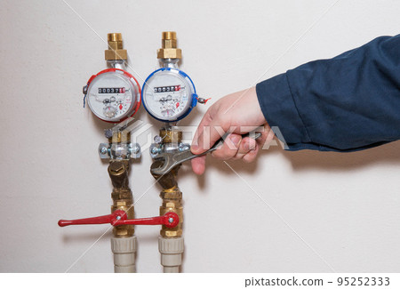 an employee removes water meters to check and replace new ones. Maintenance and repair of water meters an employee removes water meters to check and replace new ones. Maintenance and repair of water meters 95252333