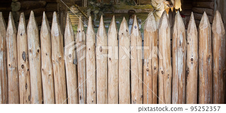 Old wooden fence made of pointed logs. Stockade, copy space for text Old wooden fence made of pointed logs. Stockade, copy space for text 95252357