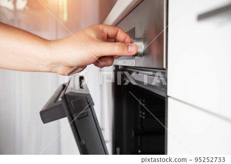 A man's hand selects a function in a modern electric oven and sets the child protection. Close-up 95252733