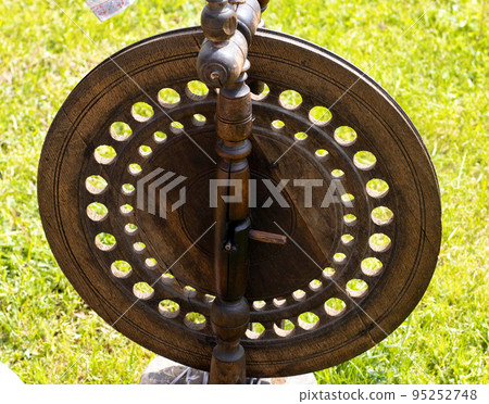 Antique vintage spinning wheel, wooden tool in the form of a wheel. Close-up 95252748