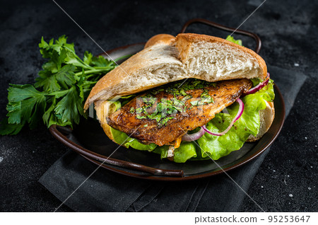 Sandwich balik Ekmek with grilled fillet of mackerel fish, tomatoes, onions and lettuce. Black background. Top view Sandwich balik Ekmek with grilled fillet of mackerel fish, tomatoes, onions and lettuce. Black background. Top view 95253647