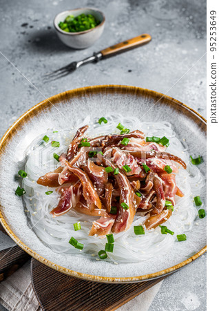 Salad with pork pig ears, glass noodles, sesame seeds and green onions. Fried pork ears in korean style. Gray background. Top view Salad with pork pig ears, glass noodles, sesame seeds and green onions. Fried pork ears in korean style. Gray background. Top view 95253649
