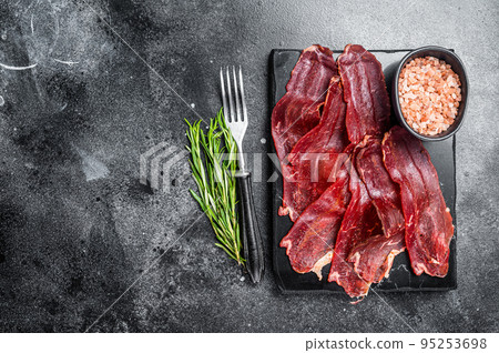 Turkish sliced pastrami (kayseri pastirma), dried beef meat with spices on marble board. Black background. Top view. Copy space 95253698