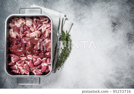 Raw chicken offals meat set, gizzards, stomachs, liver and hearts in a steel tray with herbs. White background. Top view. Copy space 95253716