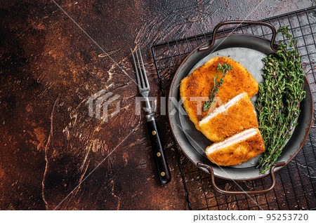 Cordon bleu chicken fillet cutlet with ham and cheese. Dark background. Top view. Copy space Cordon bleu chicken fillet cutlet with ham and cheese. Dark background. Top view. Copy space 95253720