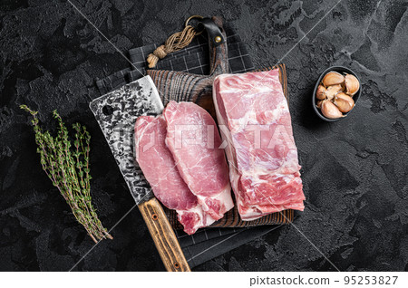 Butcher board with sliced raw pork loin fillet ready for cooking chop steaks. Black background. Top view 95253827