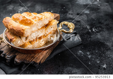 Traditional feta cheese phyllo pastry pie in rustic skillet. Black background. Top view. Copy space Traditional feta cheese phyllo pastry pie in rustic skillet. Black background. Top view. Copy space 95253913