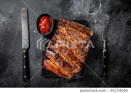 Full rack of BBQ grilled pork spare ribs on a marble board. Black background. Top view Full rack of BBQ grilled pork spare ribs on a marble board. Black background. Top view 95254040