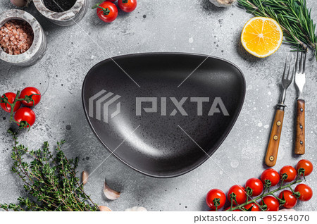 Food cooking and healthy eating background with empty rustic plate and fresh seasoning, knife, fork and vegetables ingredients. Gray background. Top view. Copy space Food cooking and healthy eating background with empty rustic plate and fresh seasoning, knife, fork and vegetables ingredients. Gray background. Top view. Copy space 95254070