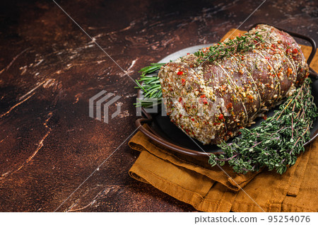Rolled meat pork roulade with rosemary and thyme. Dark background. Top view. Copy space 95254076