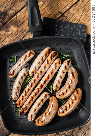Grilled homemade sausages with Beef, pork, lamb and chicken mince meat in a grill skillet. Wooden background. Top view 95254093