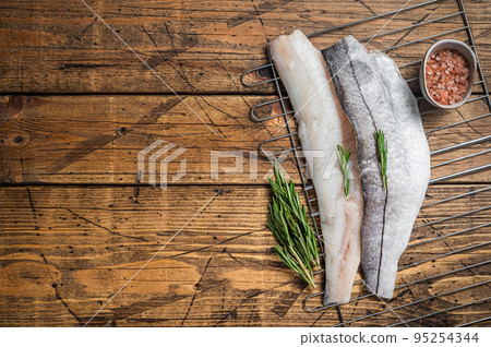 Raw fish fillets on grill with rosemary and herbs. Wooden background. Top view. Copy space 95254344