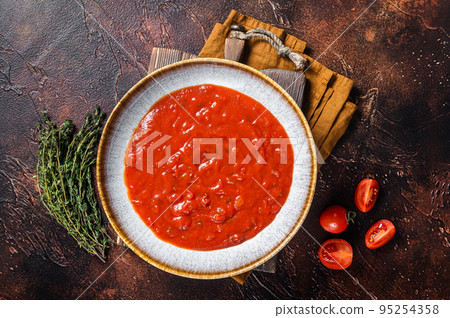 Homemade tomato Passata in rustic plate with herbs. Dark background. Top view 95254358