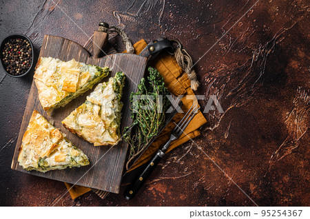 Spanakopita Greek Pie with Spinach and Cheese on wooden board. Dark background. Top view. Copy space 95254367