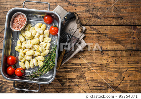 Uncooked Raw potato gnocchi in kitchen steel tray with herbs. Wooden background. Top view. Copy space Uncooked Raw potato gnocchi in kitchen steel tray with herbs. Wooden background. Top view. Copy space 95254371