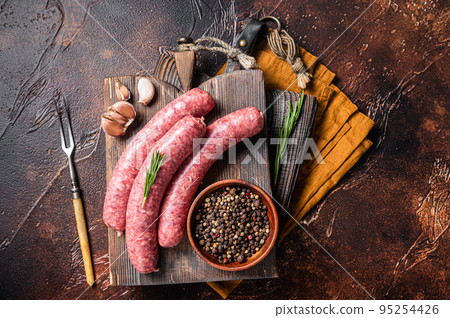 Bratwurst Raw meat sausages on wooden board with spices. Dark background. Top view Bratwurst Raw meat sausages on wooden board with spices. Dark background. Top view 95254426