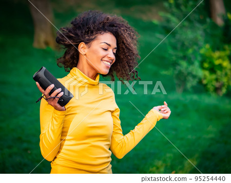 Modern trendy african american girl listening to music by wireless portable speaker.Young beautiful Modern trendy african american girl listening to music by wireless portable speaker.Young beautiful 95254440