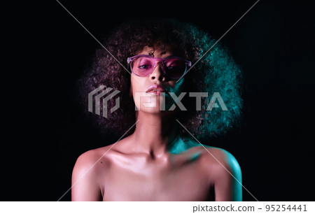 Portrait of young sexy african girl with glasses in neon light at black background. Woman with Portrait of young sexy african girl with glasses in neon light at black background. Woman with 95254441