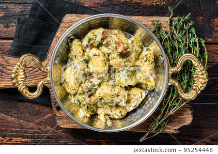 Italian Gnocchi potato pasta with spinach and parmesan in skillet. Wooden background. Top view 95254448