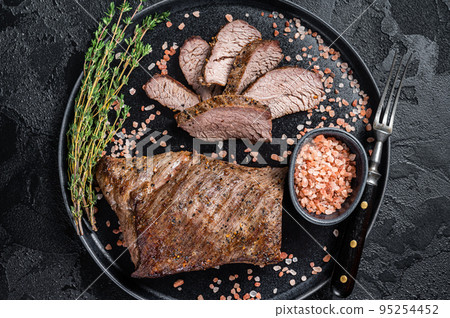 Barbecue dry aged wagyu Tri Tip beef steak on a plate with pink salt. Black background. Top view Barbecue dry aged wagyu Tri Tip beef steak on a plate with pink salt. Black background. Top view 95254452