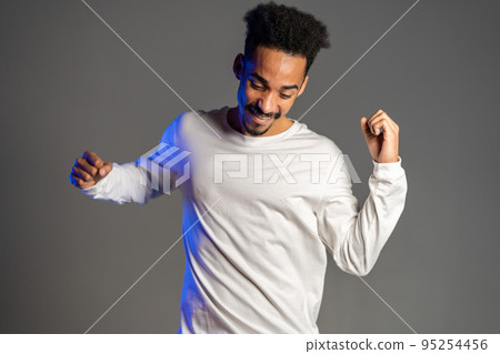 Young very active and energetic african american man in white wear smiling and dancing in good mood Young very active and energetic african american man in white wear smiling and dancing in good mood 95254456