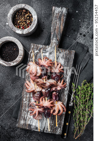 Skewers with Grilled baby mini octopuses. Black background. Top view Skewers with Grilled baby mini octopuses. Black background. Top view 95254457