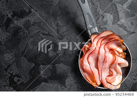 Cooking of Black Forest Ham in skillet. Black background. Top view. Copy space 95254469