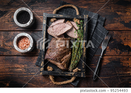 Grilled Tri Tip steak, sirloin bottom beef in a tray with herbs. Wooden background. Top view 95254493