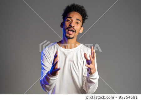 Young energetic african american man in white wear smiling and dancing in good mood on brown Young energetic african american man in white wear smiling and dancing in good mood on brown 95254581