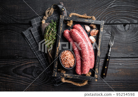 Raw sausages Bratwurst, fresh meat in wooden tray with thyme. Wooden background. Top view 95254598