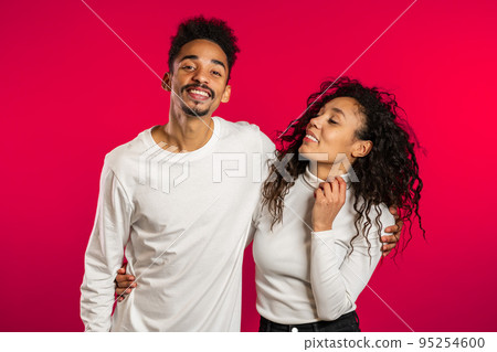 Portrait of young african american couple on red studio background. Love, holidays, happiness Portrait of young african american couple on red studio background. Love, holidays, happiness 95254600