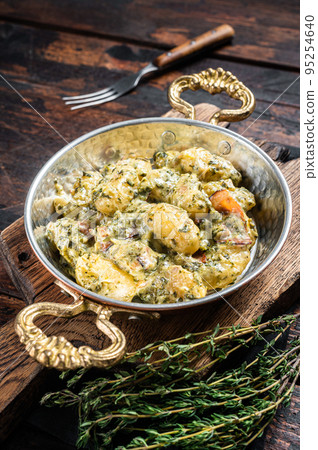 Italian Gnocchi potato pasta with spinach and parmesan in skillet. Wooden background. Top view 95254640