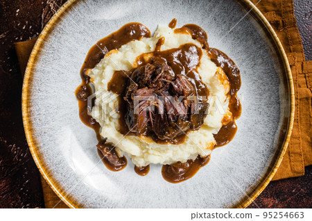 Slow cooked beef cheeks in red wine sauce with mashed potato. Dark background. Top view 95254663