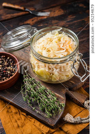 Glass jar with Homemade sauerkraut, black pepper and thyme. Wooden background. Top view 95254679