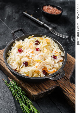 Sauerkraut in a skillet with black pepper and cranberry, Fermented cabbage. Black background. Top view Sauerkraut in a skillet with black pepper and cranberry, Fermented cabbage. Black background. Top view 95254688