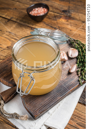 Bone broth for chicken soup in a glass jar. Wooden background. Top view 95254710