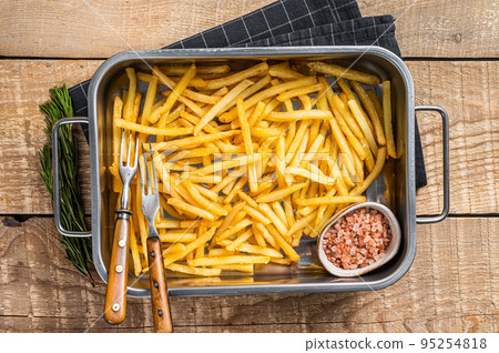 Fried French fries potatoes with salt in kitchen tray. Wooden background. Top view 95254818
