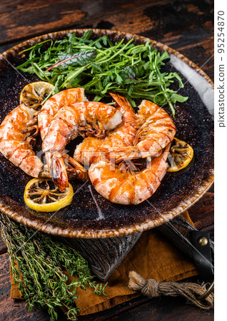 Spicy garlic Giant shrimps prawns in plate with salad. Wooden background. Top view Spicy garlic Giant shrimps prawns in plate with salad. Wooden background. Top view 95254870