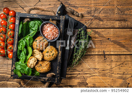 Seafood Fish balls or Fish cake with spinach and herbs in a tray. Wooden background. Top view. Copy space 95254902